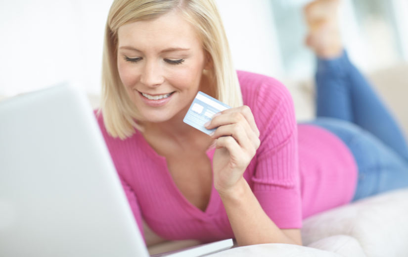 Woman in pink using a credit card to shop on a user-friendly dropshipping website, comfortably browsing on her laptop.